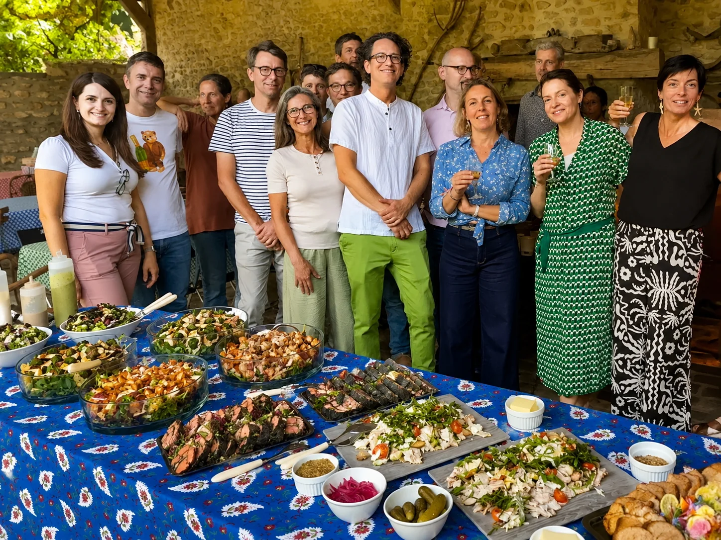 A group of guests gathered behind a long table laden with a catered spread of salads and dishes at Moulin à Rêves