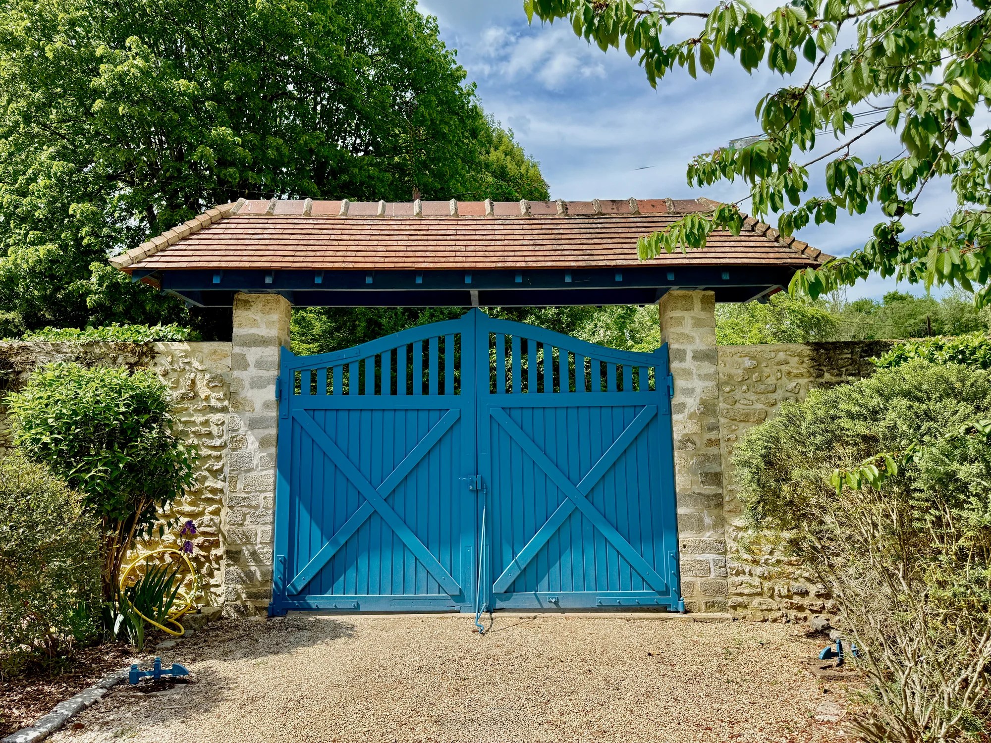 The blue wooden gates in the stone wall at the entrance to the compound of Moulin à Rêves