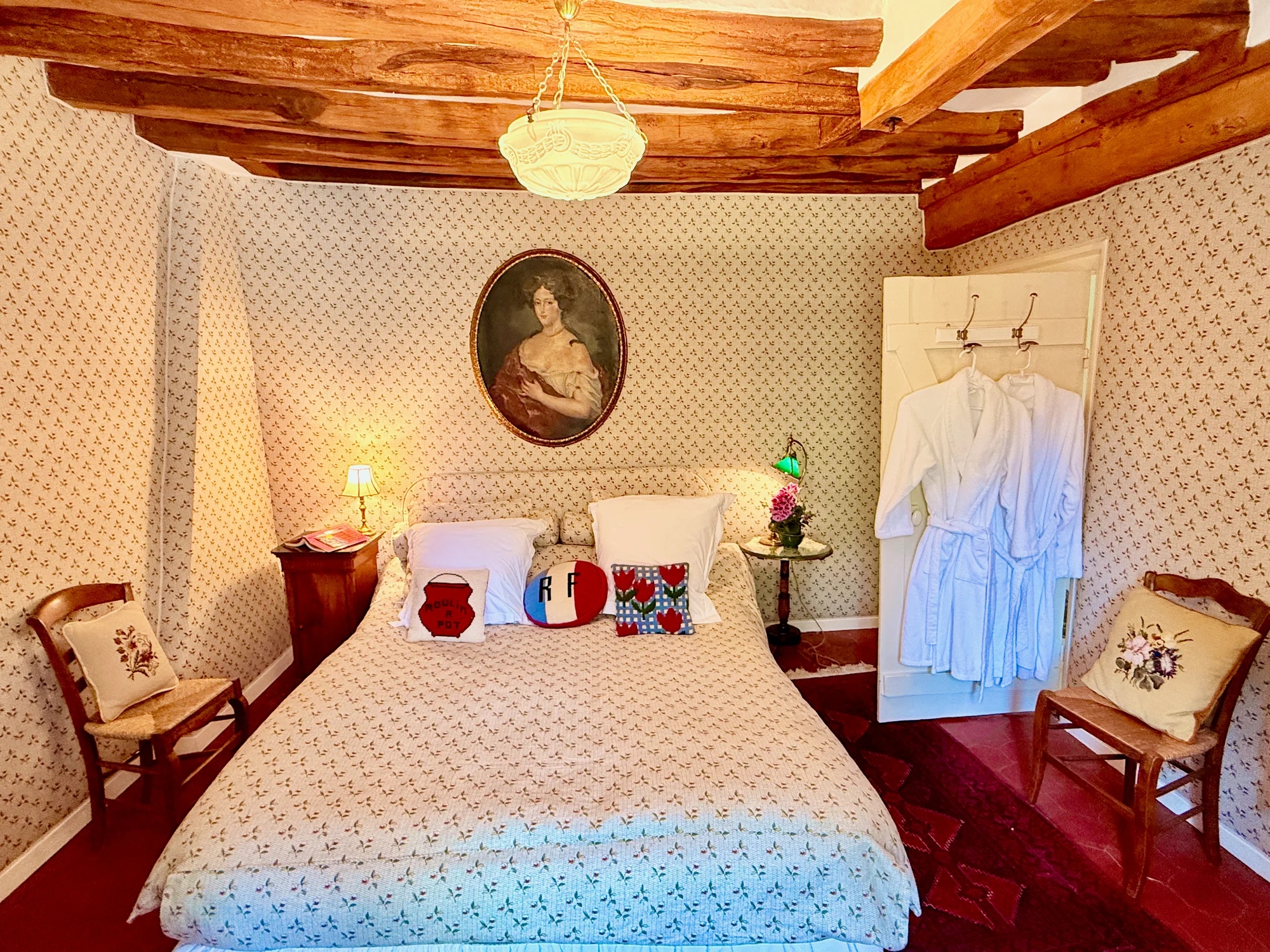 Les Cerises — the Cherry Room with a queen bed, oval portrait, and patterned wallpaper
