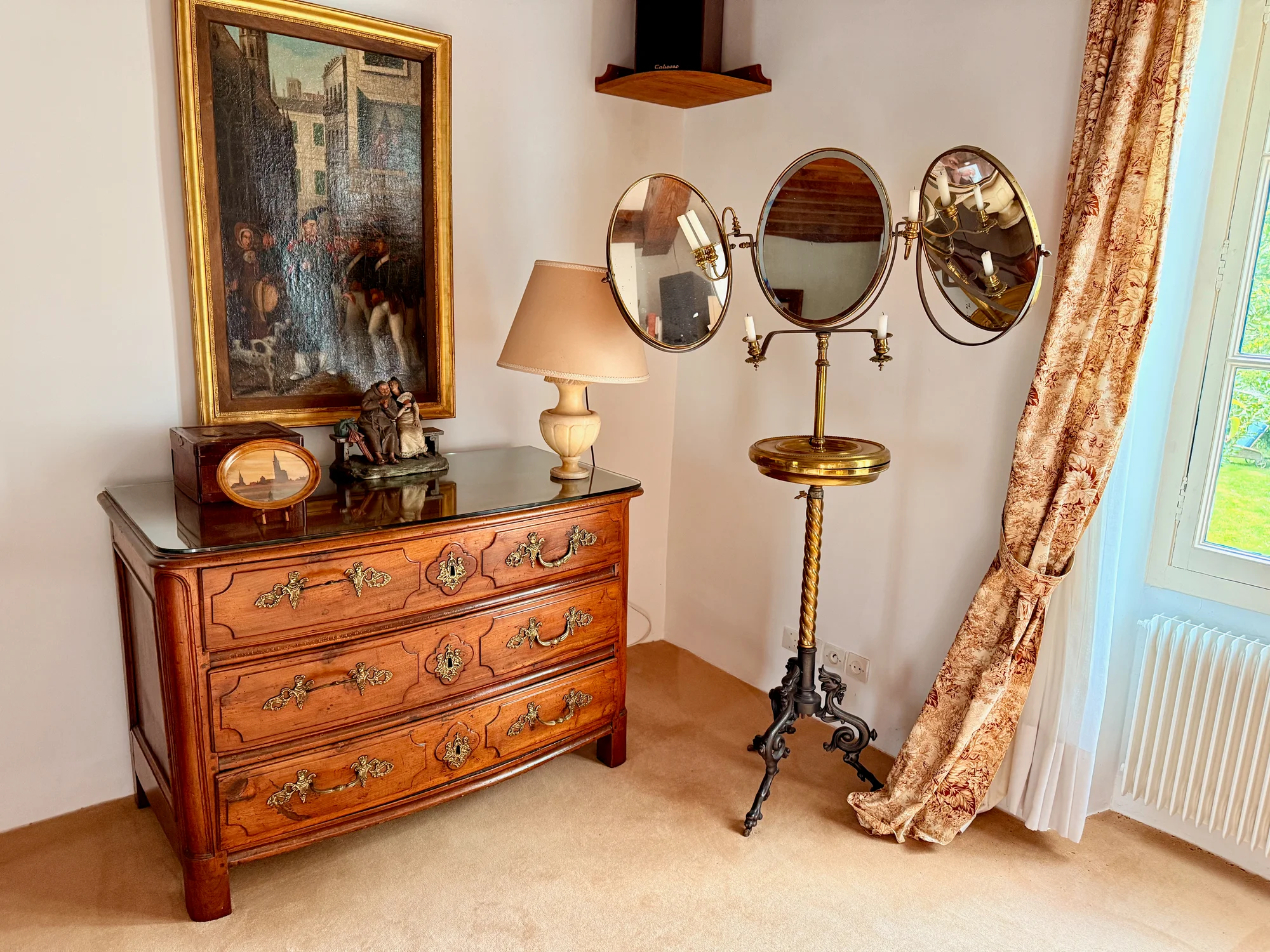 La Suite Romantique with an antique commode, oil painting, and brass triple shaving mirror at Le Moulin