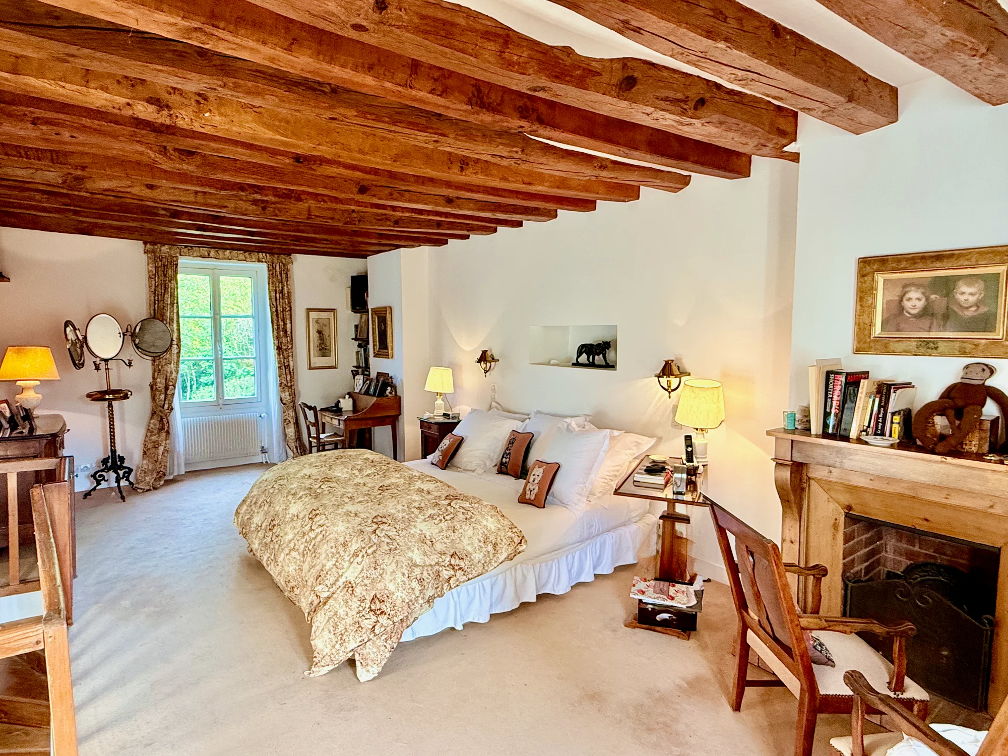 La Suite Romantique master bedroom with exposed beams and stone fireplace at Le Moulin
