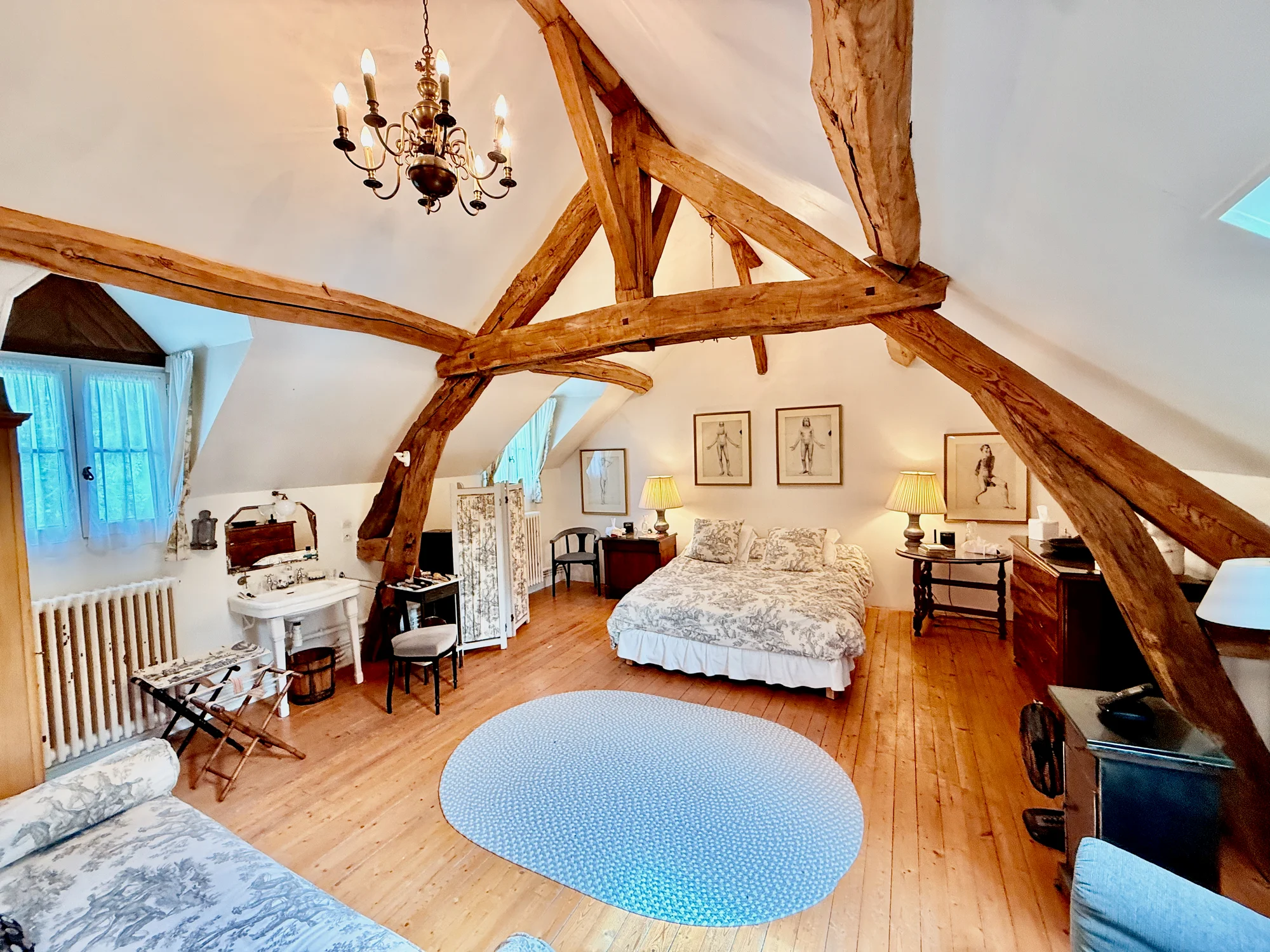 La Chambre des Artistes — sun-drenched bedroom with vaulted timber beams