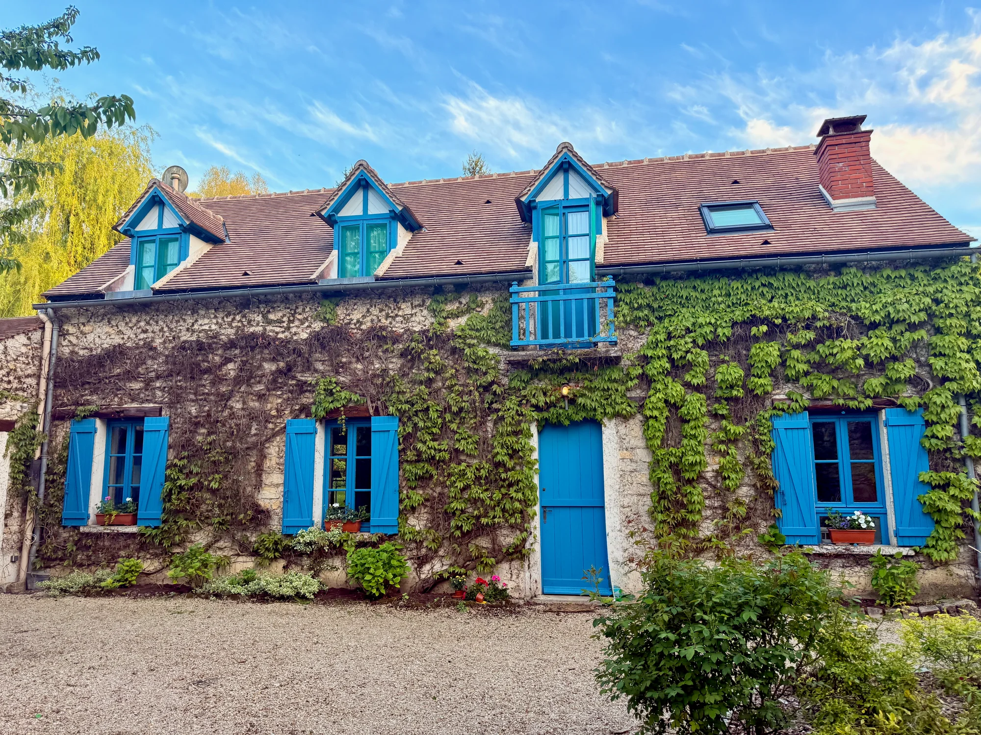 Front facade of Maison de la Rivière with dormers and ivy