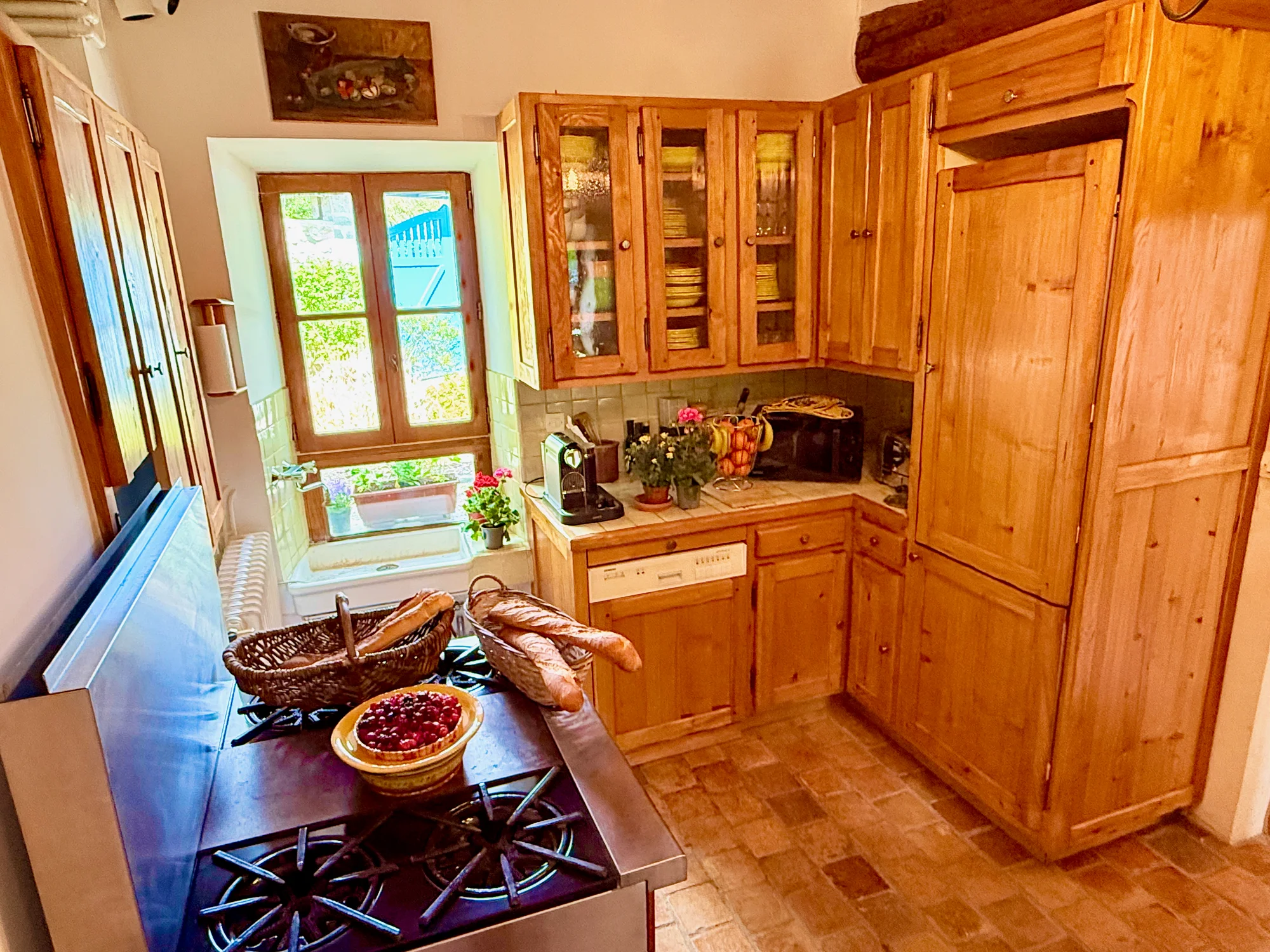 Eat-in kitchen with stone walls, beams, and a baguette on the counter at La Maison de la Rivière