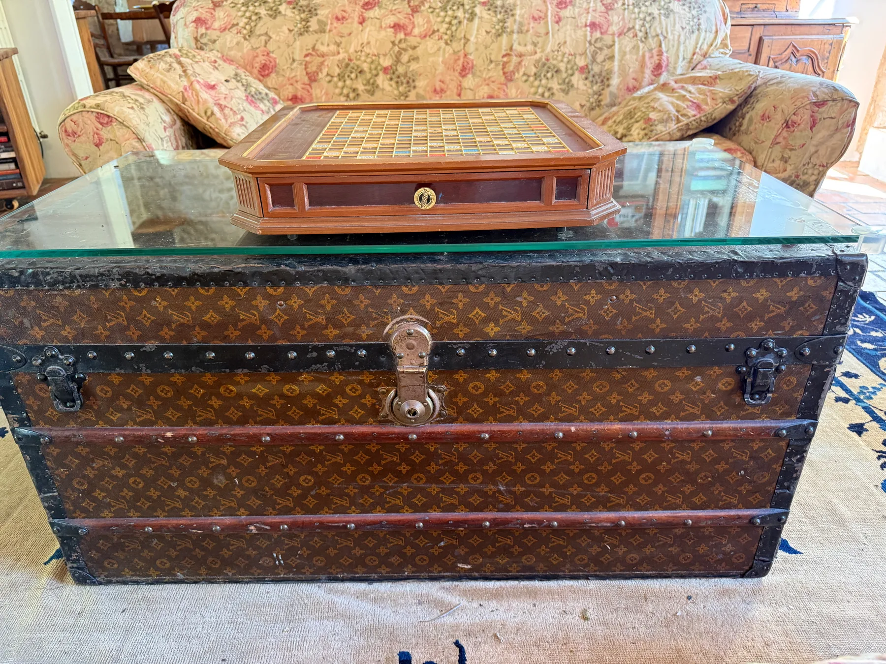 Living room with floral couches, fireplace, and the Louis Vuitton trunk coffee table