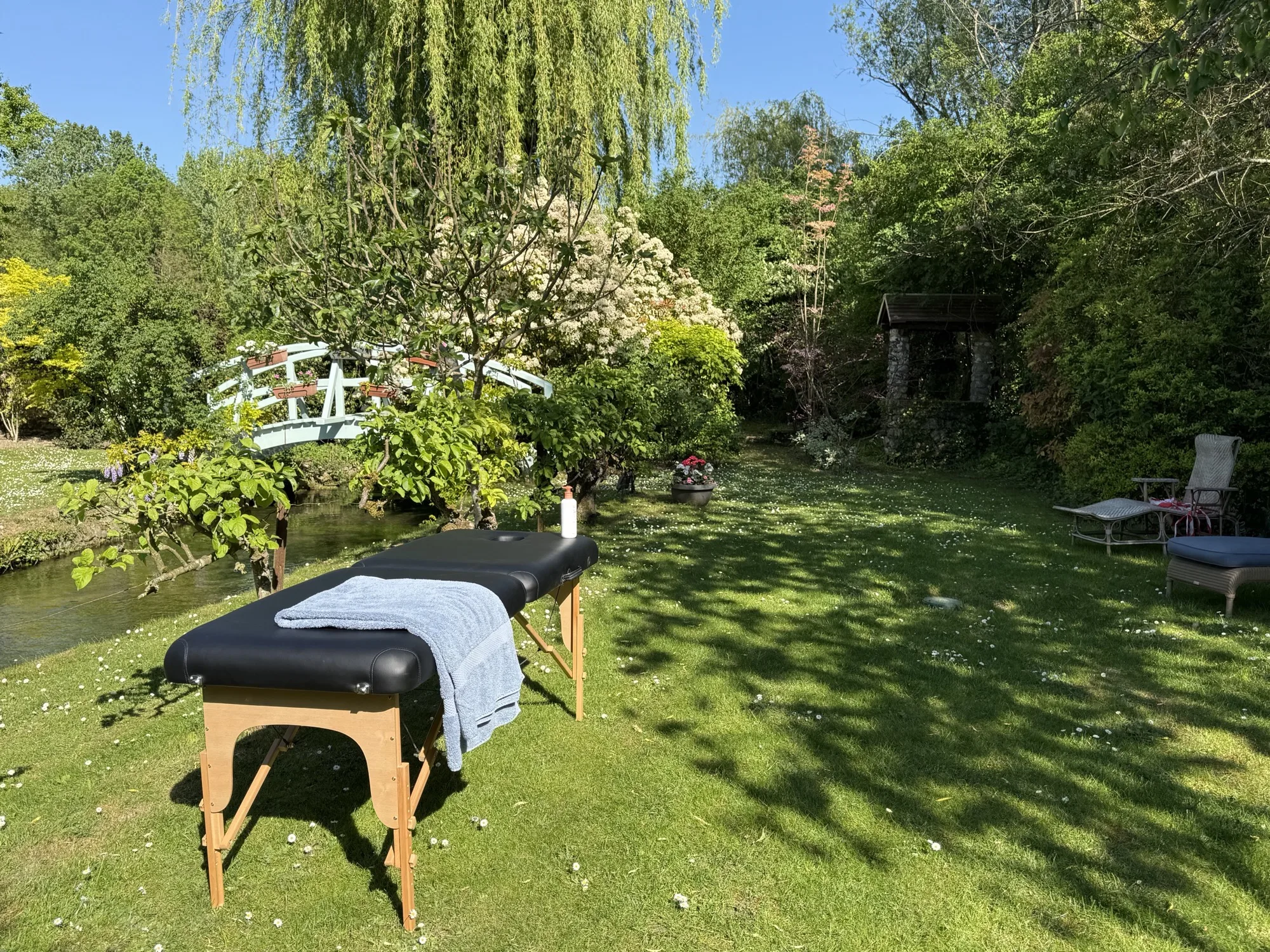 Massage table by the millstream beneath the Giverny-style bridge