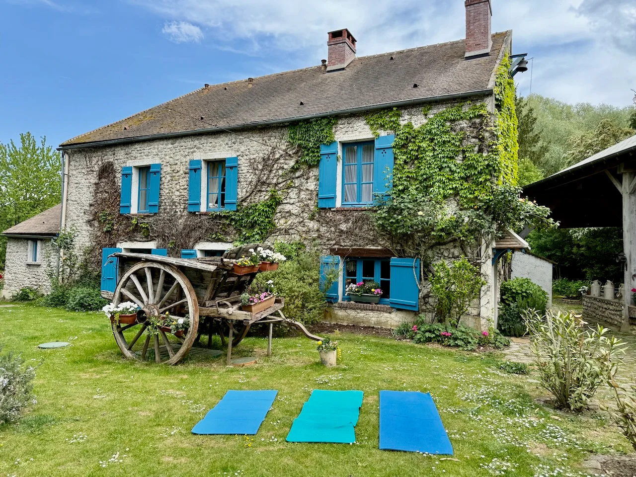 Yoga practice on the lawn outside Le Moulin's blue-shuttered facade