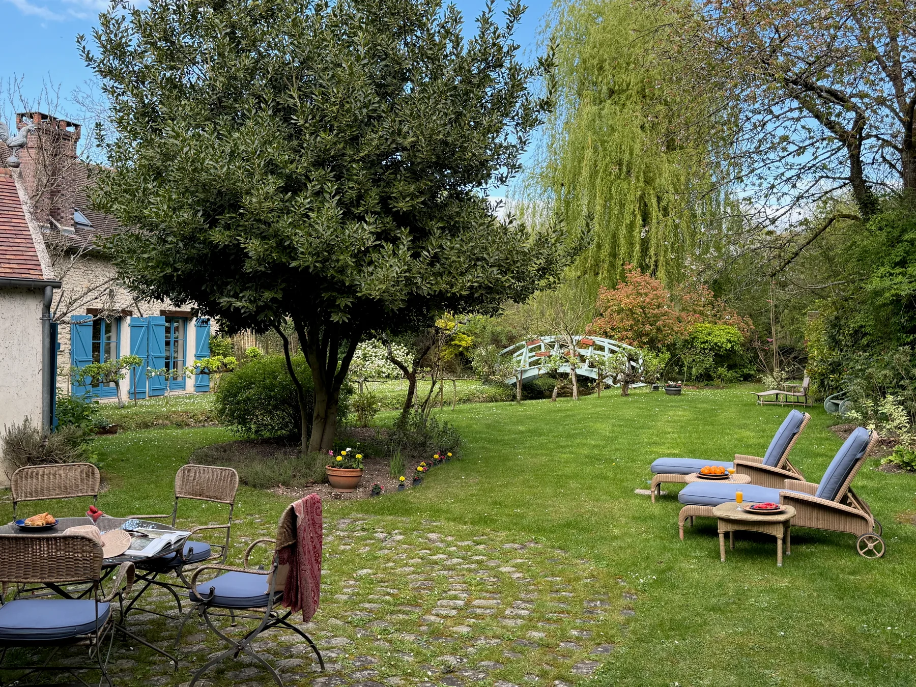 Garden chaises on the lawn with the bridge in view at Moulin à Rêves